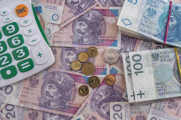 Neue, saubere, glatte polnische Zloty-Banknoten sind verstreut und es ist Zeit für einen neuen Taschenrechner