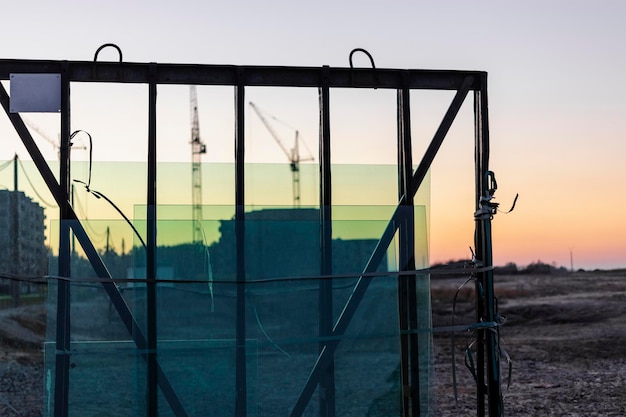 Neue versiegelte Glaseinheiten auf der Baustelle vor dem Hintergrund eines Sonnenuntergangshimmels Lagerung und Vorbereitung beim Fenstereinbau Spiegelung der Abendsonne in neuen doppelt verglasten Fenstern