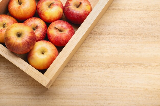 Neuer Apfelhintergrund mit Exemplarplatz. Rote Äpfel in der Kiste auf Holztisch
