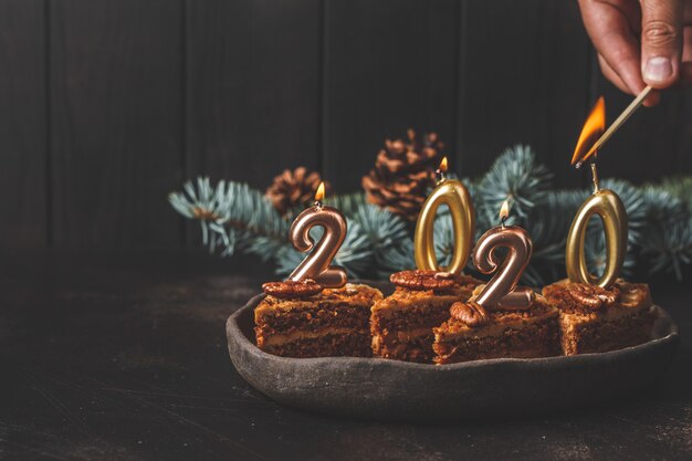 Neues Jahr 2020. Festlicher Kuchen mit Kerzen auf dunkler Tabelle, Kopienraum.