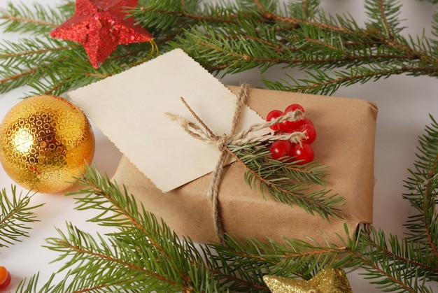 Neues Jahr-Handwerk, das Geschenkbox unter grünen Kieferniederlassungen und Weihnachtsdekorbällen einwickelt