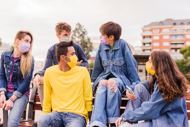 Neues normales Corona-Virus-Leben mit einer gemischtrassigen Gruppe junger Studenten, die Gesichtsmaske für Pandemie trägt