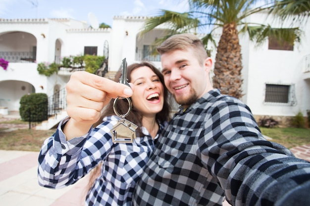 Neues Zuhause, Immobilien und Umzugskonzept - Lustiges junges Paar zeigt Schlüssel vom neuen Haus.