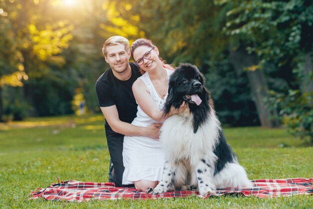 Neufundländer spielt mit Mann und Frau im Park