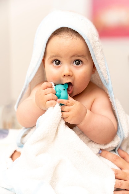Neugeborener Junge, der sich nach dem Bad oder der Dusche im Bett entspannt Neugeborener Junge mit hochwertigem Foto des Spielzeugbären