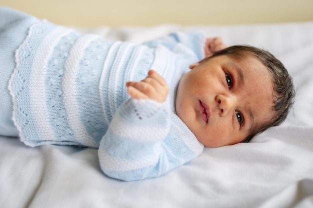 Neugeborener Junge im Krankenhaus am ersten Lebenstag, der zum ersten Mal die Augen öffnet