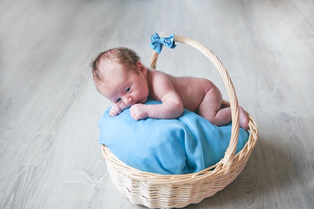 Neugeborener kleiner Junge im Korb blaue Augen und Farben Kind glücklich lächelnd und mit Blick auf die Kamera