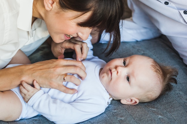 Neugeborenes auf dem Bett liegend, Mutter schaut ihr Baby an, Papa schaut sein Baby an, kleiner Junge