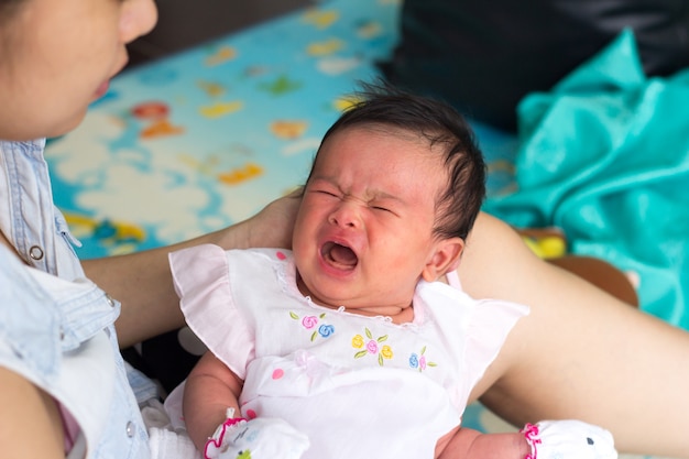 Neugeborenes Baby auf den Händen der Mutter. Mutter, die Kopf ihres neugeborenen Babys in den Händen hält.