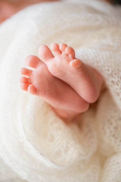 Neugeborenes Baby auf einer weißen Decke winzige Babyfüße Nahaufnahme neugeborenes Grußkartenkonzept