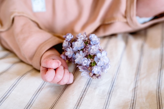 Neugeborenes Baby, das eine Blume hält