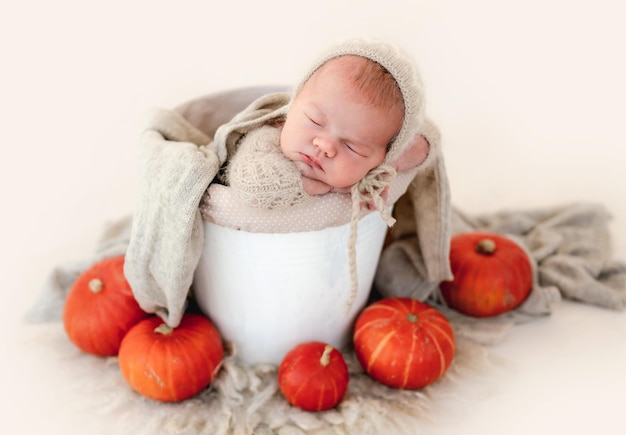 Neugeborenes Baby, das im mit Kürbissen verzierten Becken schläft. Säuglingskind, das sich während des Studio-Fotoshootings ausruht
