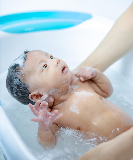 Neugeborenes Baby, das unter der Dusche badet