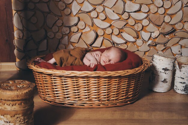 Neugeborenes Baby eingewickelt in einer Decke, die in einem Korb schläft
