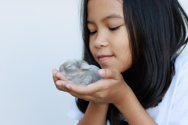 Neugeborenes Baby holland lop Bunny in Kinderhänden Asiatisches Mädchen, das mit Zärtlichkeit und Liebe ein winziges Häschen in der Hand hält Die Menschen kümmern sich um ein Haustier Neues Leben des Tierkonzepts