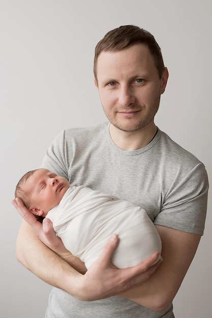 Neugeborenes Baby im Arm des Vaters auf Bett Postkarte Vatertag Kinderschutztag Weltglückstag Lächelndes Kind und Mann