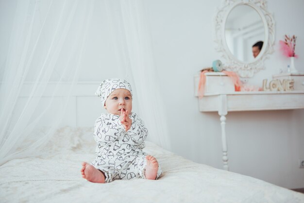 Neugeborenes Baby in einem Anzug auf einem weichen Bett im Studio gekleidet.