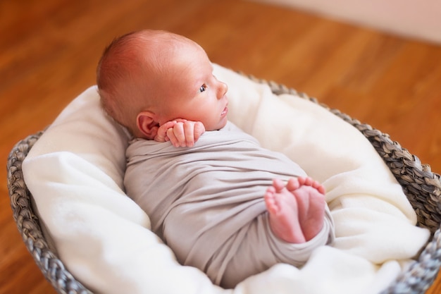 Neugeborenes Baby in einem Korb. Kleine Hände und Füße des Kindes. Baby wickeln