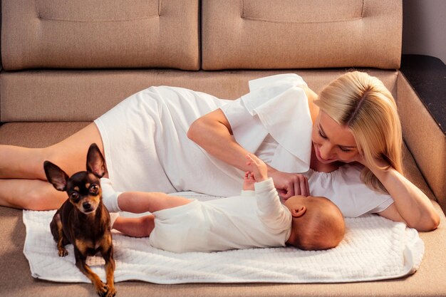 Neugeborenes Baby in einer zärtlichen Umarmung der Mutter, die auf dem Bett im Schlafzimmer liegt