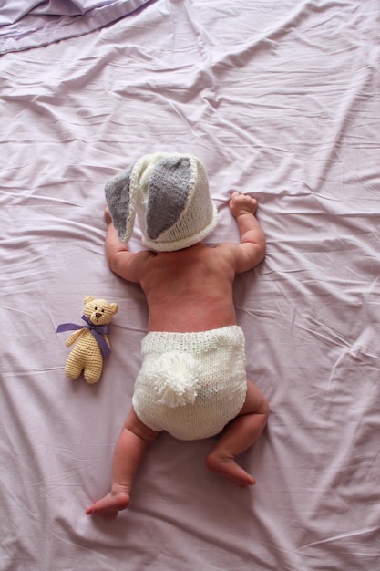 Neugeborenes Baby liegt auf seinem Bauch auf einem lila Laken