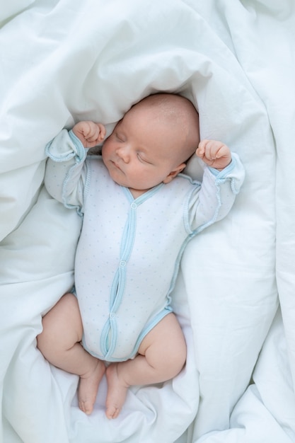 Neugeborenes Baby schläft sieben Tage in einem Kinderbett zu Hause auf einem Baumwollbett, Draufsicht.