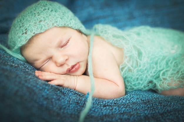 Neugeborenes Baby schläft süß auf einem blauen Teppich in blauer Mütze