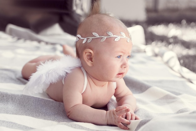 Foto neugeborenes mädchen mit blauen augen, einem lorbeerkranz in ihrem haar und engelswinden