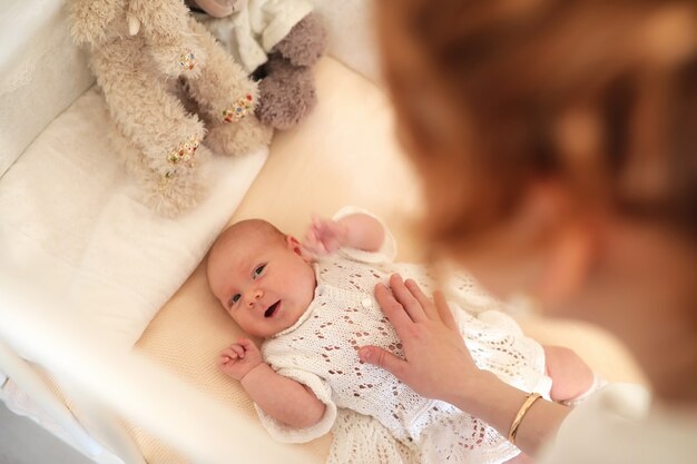 Neugeborenes süßes Baby liegt in der Krippe und schaut Mutter an