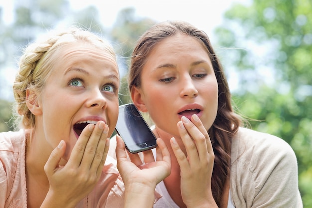 Neugierige Freunde, die auf Telefonanruf im Park hören