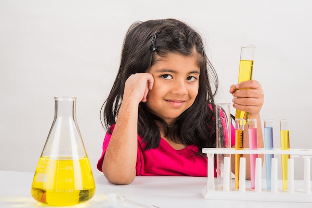 Neugierige kleine indische Schulkinder oder Wissenschaftler, die Naturwissenschaften studieren, mit Chemikalien oder Mikroskopen im Labor experimentieren, selektiver Fokus