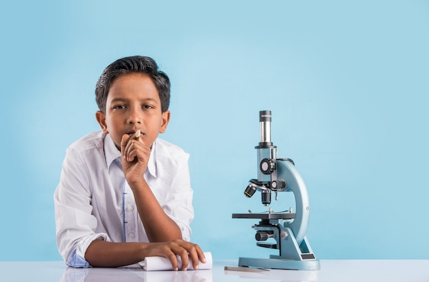 Neugierige kleine indische Schulkinder oder Wissenschaftler, die Naturwissenschaften studieren, mit Chemikalien oder Mikroskopen im Labor experimentieren, selektiver Fokus