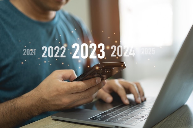 Neujahr 2023 Konzept Beginnen Sie ein frohes neues Jahr 2023 Geschäftsmann Investoren mit Laptop und Handy Touchscreen virtuelle 2023 Jahre Diagramm Unternehmensplanung Strategie Geschäftstrends Investition