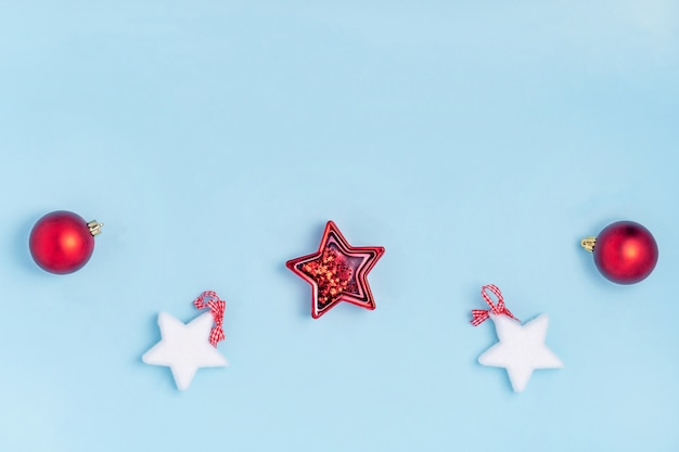 Neujahr und Weihnachten Komposition. Rote und weiße Weihnacht spielt - Sterne, Weihnachtsbälle auf Pastellhintergrund des blauen Papiers. Draufsicht, flache Lage, Kopienraum