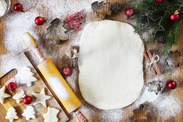 Neujahrs-Delikatesse, die Butterkekse in verschiedenen Formen auf einem Holztisch mit Weihnachtszubehör kocht