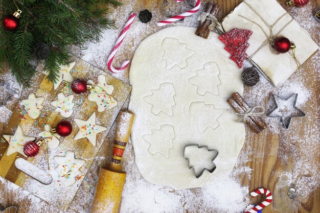 Neujahrs-Delikatesse, die Butterkekse in verschiedenen Formen auf einem Holztisch mit Weihnachtszubehör kocht