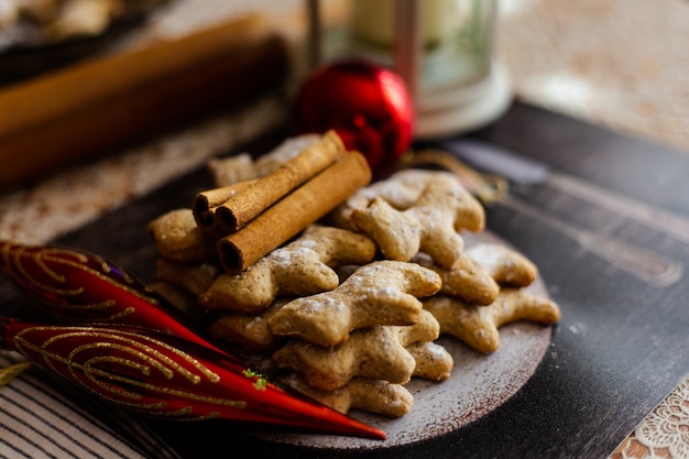 Neujahrs Ingwerplätzchen in Form eines Stiers und Zimtstangen auf einem Teller