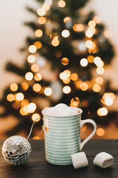 Neujahrs- und Weihnachtshintergrund mit einer Tasse Kaffee mit Marshmallows und Kerzen auf Weiß