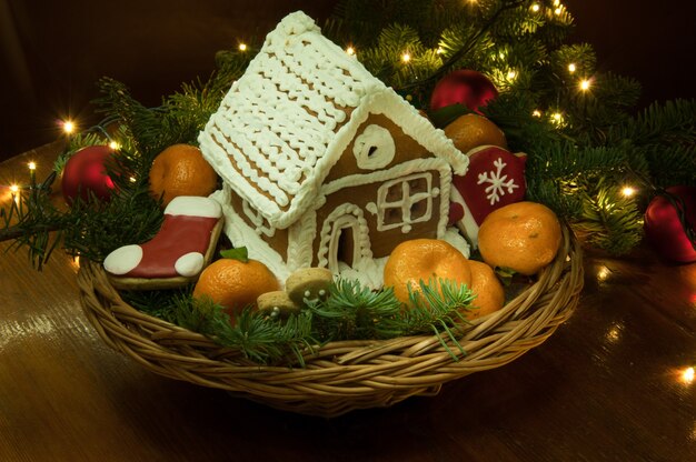 Neujahrs-Weihnachtsplätzchen mit Mandarinen und einem kleinen Haus im Korb