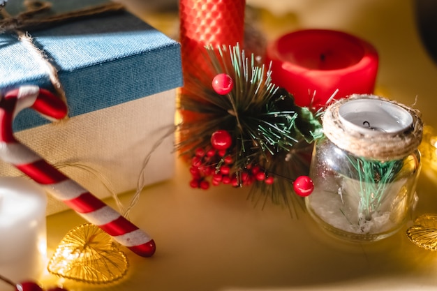 Neujahrsatmosphäre Neujahrsgeschenkkerze und Weihnachtsspielzeuggirlande auf gelbem Hintergrund