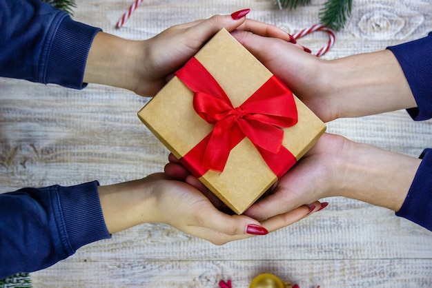 Neujahrsgeschenke in den Händen auf einem hölzernen Hintergrund. Weihnachten selektiver Fokus