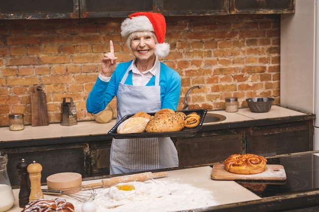 Neujahrskochen. Porträt der attraktiven älteren älteren Frau kocht auf Küche. Großmutter macht leckeres Weihnachtsbacken.