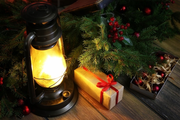 Neujahrskomposition aus Zweigen von Weihnachtsbäumen, die mit Kugeln verziert sind Vintage-Lampe mit brennenden Kerzen und Kisten mit Geschenken