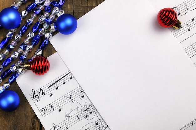 Neujahrskomposition Weihnachtsbaumschmuck auf dem Tisch und Blatt mit Musiknoten