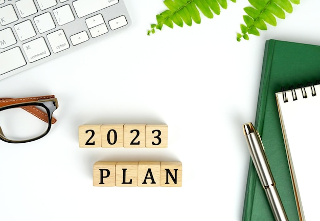 Neujahrsplan. Pläne für 2023. Tastatur, Notizbuch und Stift, 2023 PLAN-Wort ist auf Holzblock geschrieben,