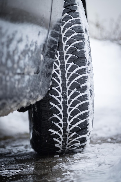 Neumático de coche en invierno en la carretera cubierta de nieve cerca de la imagen