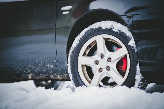 Neumático de coche en invierno en la carretera cubierta de nieve cerca de la imagen