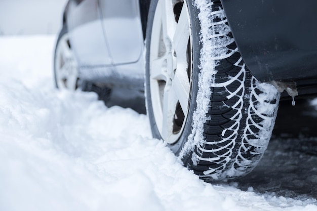 Neumático de coche en invierno en la carretera cubierta de nieve cerca de la imagen