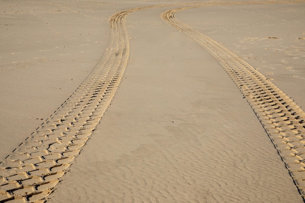 Neumático de coche con vista al desierto Pistas en la costa de la playa de arena