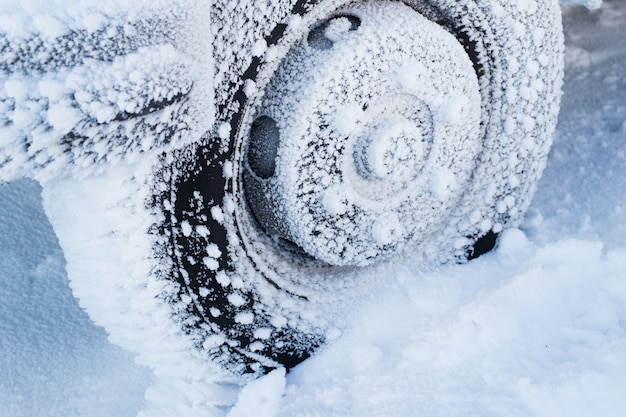 Neumático de invierno Coche en camino de nieve. Neumáticos en detalle de la carretera nevada.