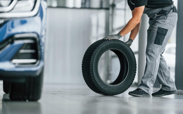 Neumático en el piso El hombre en uniforme está trabajando en el autosalon durante el día